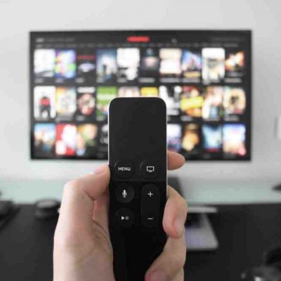 Person holding a remote to TV showing Netflix