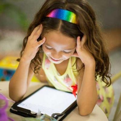Girl sitting at a table playing on a tablet