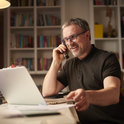 Man sitting in front of laptop using home phone